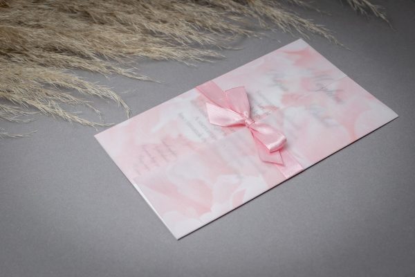 Elegáns esküvői meghívó gyöngyház papírra nyomtatva, rózsaszín virágmintás pauszpapírral és rózsaszín szatén szalaggal díszítve.